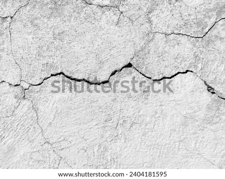 The wall of an old building with crumbling plaster and many winding, deep cracks. Copy space. Black and white photo. Selective focus. Royalty-Free Stock Photo #2404181595