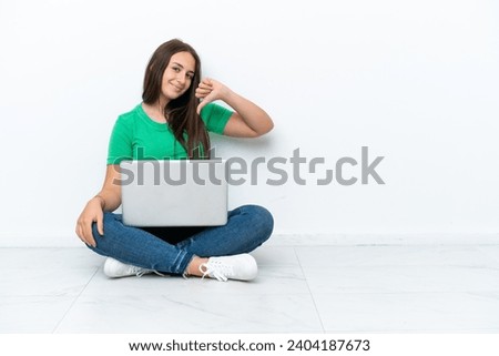 Young Ukrainian woman with a laptop sitting on floor proud and self-satisfied
