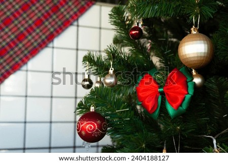 Close up of Christmas tree flashing colors with reflection in window. focus on red bow. Close up of colorful balls for decorating the Christmas tree. Christmas tree with colorful balls and flashing l