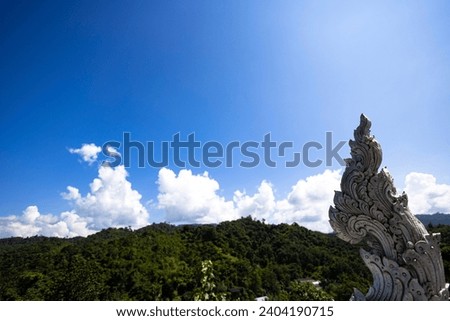 White Naga, Serpent statue on roof of Buddhist temple with blue sky background.