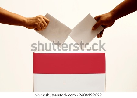 Indonesian election day.  election box with red and white flag.  hand inserts ballot paper into election box.  presidential and vice presidential elections in Indonesia Royalty-Free Stock Photo #2404199629