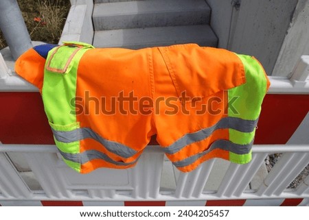 Short work trousers hang over a warning barrier to dry