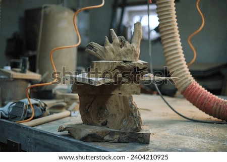 In the woodshop's ambiance, a tower of burl wood pieces stands as a testament to the raw beauty of nature's creations, soon to be shaped by skilled hands. Royalty-Free Stock Photo #2404210925