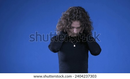 Stressed young woman rubbing neck trying to appease mental anguish while standing on blue background Royalty-Free Stock Photo #2404237303