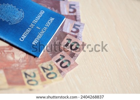 Brazilian work card and social security blue book and reais money bills close up