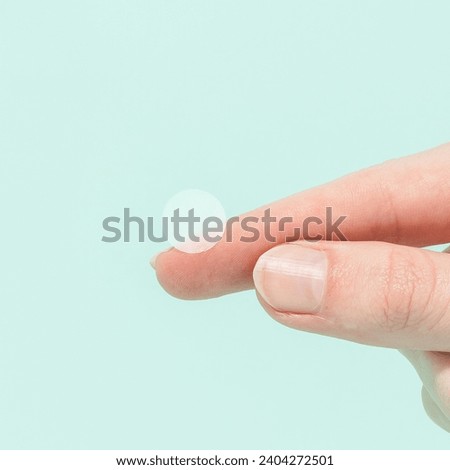 Woman holding pimple patch on green background  Royalty-Free Stock Photo #2404272501