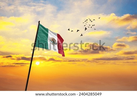 Waving flag of Mexico against the background of a sunset or sunrise. Mexico flag for Independence Day. The symbol of the state on wavy fabric.