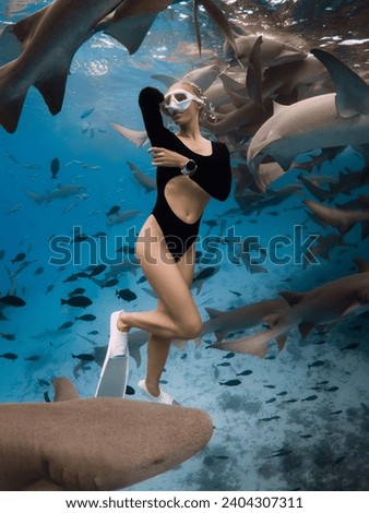 Attractive woman dives and posing with the shark in a tropical ocean in the Maldives