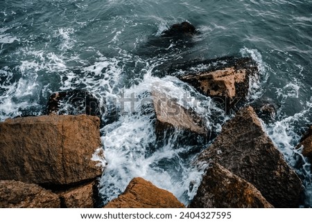 Water with stones on the beach concept photo. Mediterranean winter stormy seaside. Underwater rock with algae. The view from the top, nautical background. 