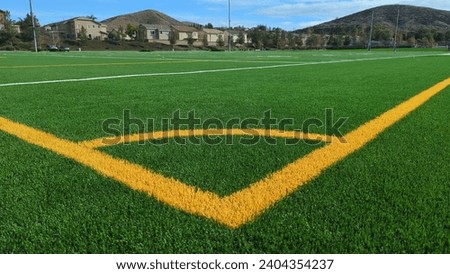 Low angle view from corner arc down sideline of a combination American football and soccer field. Yellow lines denote the soccer field.