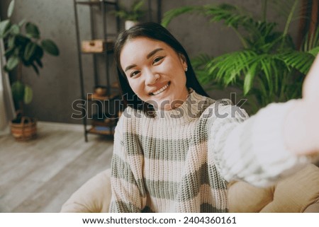 Close up young woman wear casual clothes do selfie shot pov on mobile cell phone sits on armchair stay at home hotel flat rest relax spend free spare time in living room indoor. People lounge concept