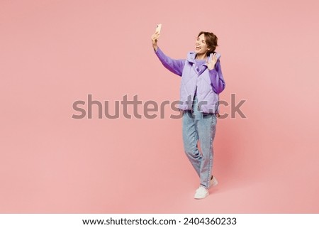 Full body young woman wear purple vest sweatshirt casual clothes doing selfie shot on mobile cell phone post photo on social network isolated on plain pastel light pink background. Lifestyle concept