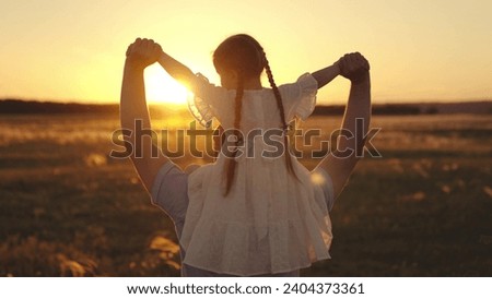 Girl chooses place on field with father to launch lanterns to celebrate birthday. Girl sings sitting on shoulders of father as walking across field. Preschooler girl talks about cartoons to father