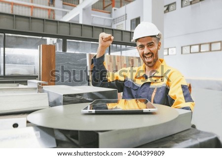 Male spanish worker technician with smile happy and having fun working in factory industrial company sitting with fist raised positive attitude strong and confident looking at camera factory office. Royalty-Free Stock Photo #2404399809