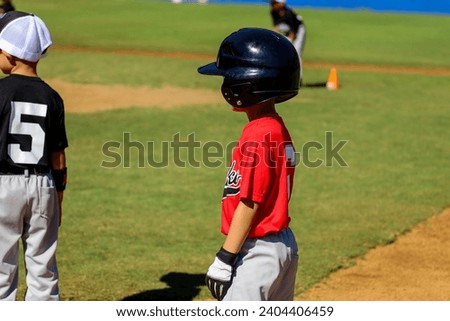 View of a 4-5 year old standing on 1st base at a T-ball game.