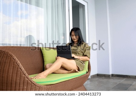 Asian woman shopping online using computer tablet on home balcony with nature view