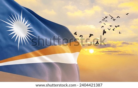 Waving flag of Marshall Islands against the background of a sunset or sunrise. Marshall Islands flag for Independence Day. Royalty-Free Stock Photo #2404421387