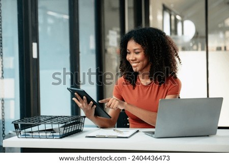 Young woman typing on tablet and laptop while sitting at the working white table modern office
