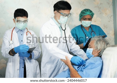 Asian doctor team check old senior lady patient for disease to motivation new normal to treat infection Covid-19 Coronavirus at hospital ward. Royalty-Free Stock Photo #2404446017