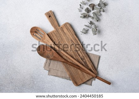 Cutting board with wooden kitchen spoons and linen napkin. Kitchen background with free space for text.