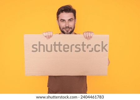 Man with blank banner ad on studio background. Portrait of attractive man holding empty blank poster. Man showing blank poster. Male presenting signboard, billboard or banner with copy space.
