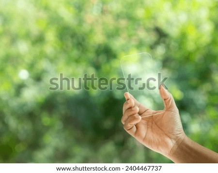 Hand holding and showing transparent tablet device. Business, natural green bokeh background,technology concept,alternative energy,conservative clean energy .