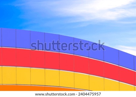 Geometric pattern background of colorful curve aluminium composite tiles wall decoration on high section outside of modern building against blue sky Royalty-Free Stock Photo #2404475957