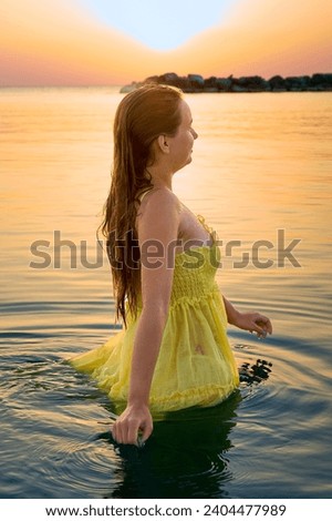 Beautiful woman relaxing on the beach in the morning after swimming against the backdrop of sunrise in the ocean.