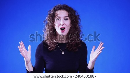 Happy Woman Raising Arms and Exclaiming WOW in Slow-Motion on Blue Background