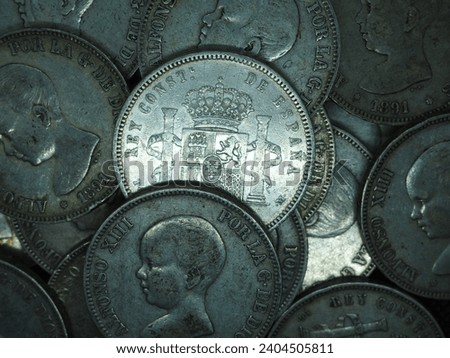 Five peseta coins, silver coins of Alfonso XIII on a black background.

