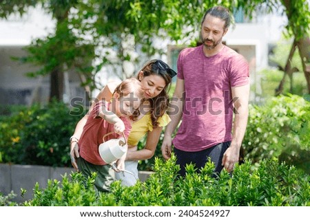 Father mother and son Caucasian family Plant trees and water them in the natural garden to reduce global warming growth and take care of the natural world. The concept of family relationships learning Royalty-Free Stock Photo #2404524927