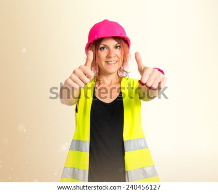 Worker woman making Ok sign over ocher background
