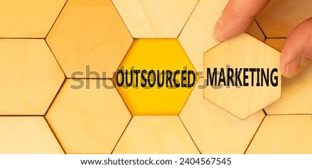 Outsourced marketing symbol. Concept words Outsourced marketing on beautiful wooden puzzle. Beautiful yellow table background. Businessman hand. Business Outsourced marketing concept. Copy space.