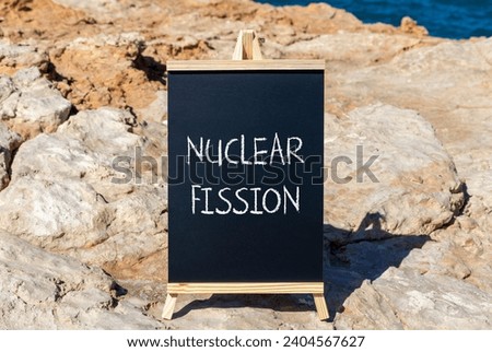 Nuclear fission symbol. Concept words Nuclear fission on beautiful black chalk blackboard. Chalkboard. Beautiful stone sea sky background. Business science nuclear fission concept. Copy space. Royalty-Free Stock Photo #2404567627