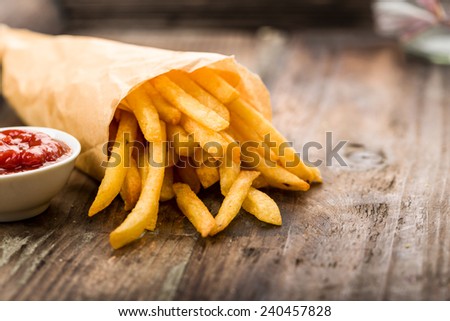 Fresh fried french fries with ketchup on wooden background Royalty-Free Stock Photo #240457828