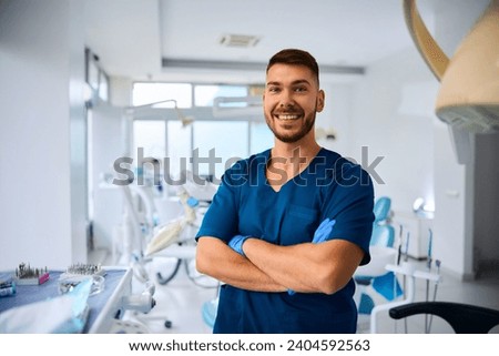 Happy dentist with arms crossed at dental clinic looking at camera. Copy space. Royalty-Free Stock Photo #2404592563