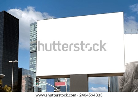 A large information display for outdoor advertising is installed on the street near the road against the backdrop of skyscrapers.