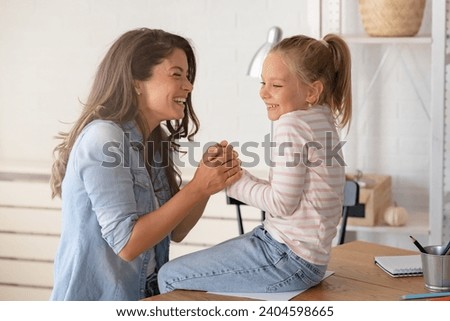 A joyful and affectionate moment unfolds as a cheerful mother and her daughter share warm smiles, cuddling and having fun together.