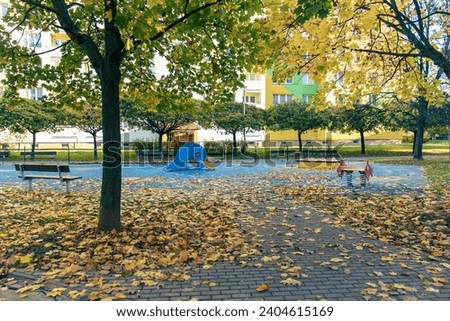 photo of an empty playground during the fall season. Playground. Slide, equipment. Empty playground. Fallen leaves, trees, park, sidewalk, autumn