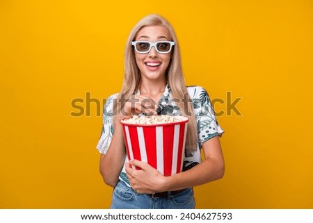 Photo of impressed girl with long hairdo dressed shirt in 3d glasses eat popcorn watch excited movie isolated on yellow color background