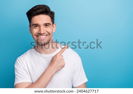Photo of positive good mood man dressed white t-shirt pointing finger empty space isolated blue color background