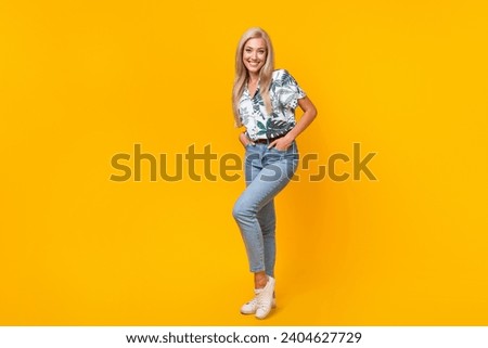 Full size photo of stylish adorable girl dressed print shirt jeans arms in pockets near empty space isolated on yellow color background