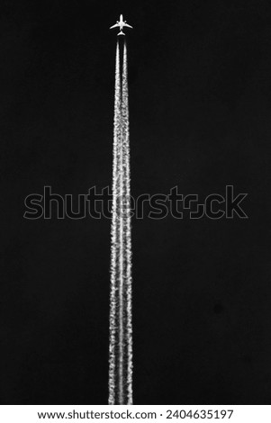Airplane in the sky with white trace on the black background. Royalty-Free Stock Photo #2404635197