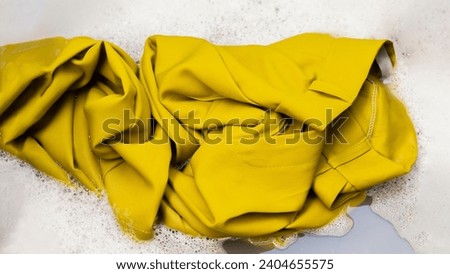 Soaking yellow pants before washing them by hand in the sink