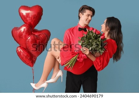 Young couple with roses and balloons on blue background. Valentine's Day celebration