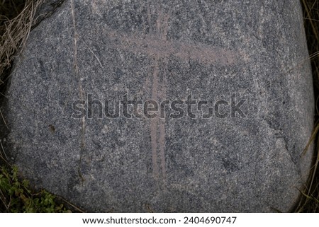 close up of gray granite rock with red painted cross on it
