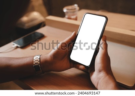 Close up view of a man using blank screen smartphone in cafe.