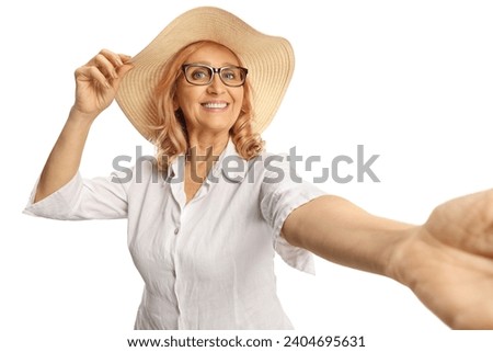 Beautiful middle aged woman with a straw hat taking a selfie isolated on white background