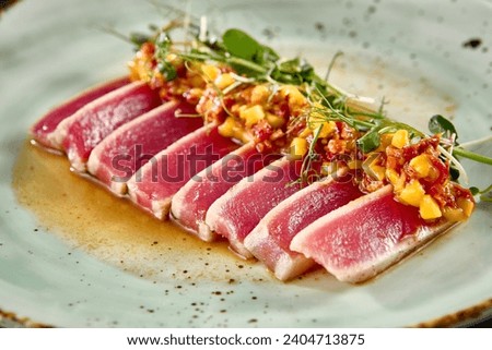 Seared tuna tataki with mango salsa and ponzu sauce on a speckled ceramic plate. Royalty-Free Stock Photo #2404713875