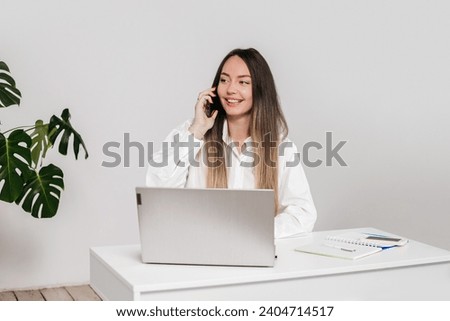 businesswoman is talking on the phone with her business partner while sitting at her desk